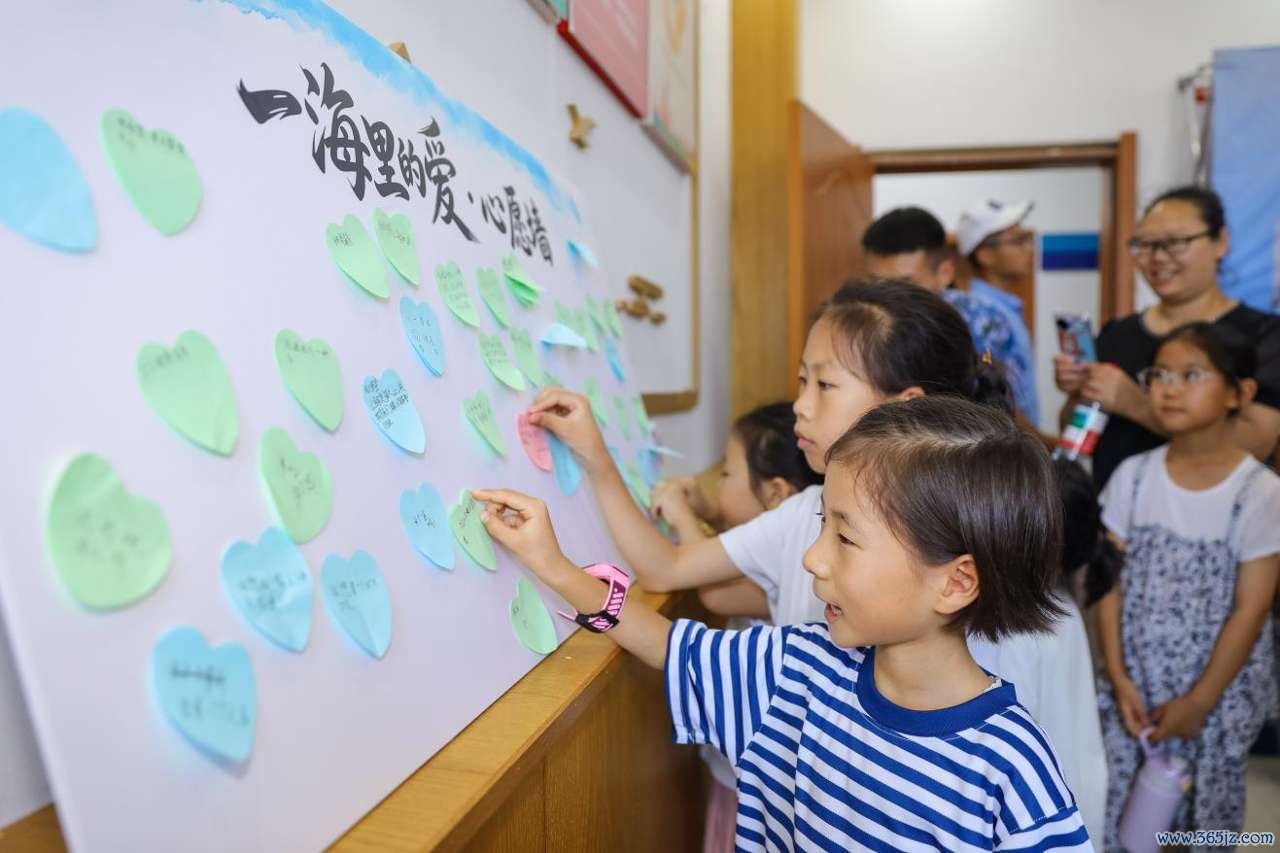 2026年7月30日，在山东省青岛西海岸新区滨海街道三沙路社区开展的“一海里的爱”公益活动中，小朋友张贴自己的心愿卡。张鹰 摄 (2)