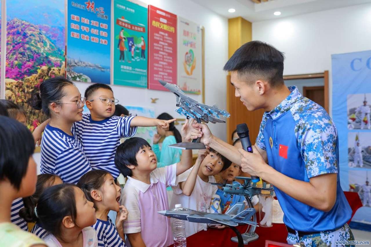 2026年7月30日，在山东省青岛西海岸新区滨海街道三沙路社区开展的“一海里的爱”公益活动中，爱基金逐梦深蓝讲师团讲师利用模型为小朋友们介绍海军战机知识。张鹰 摄 (2)