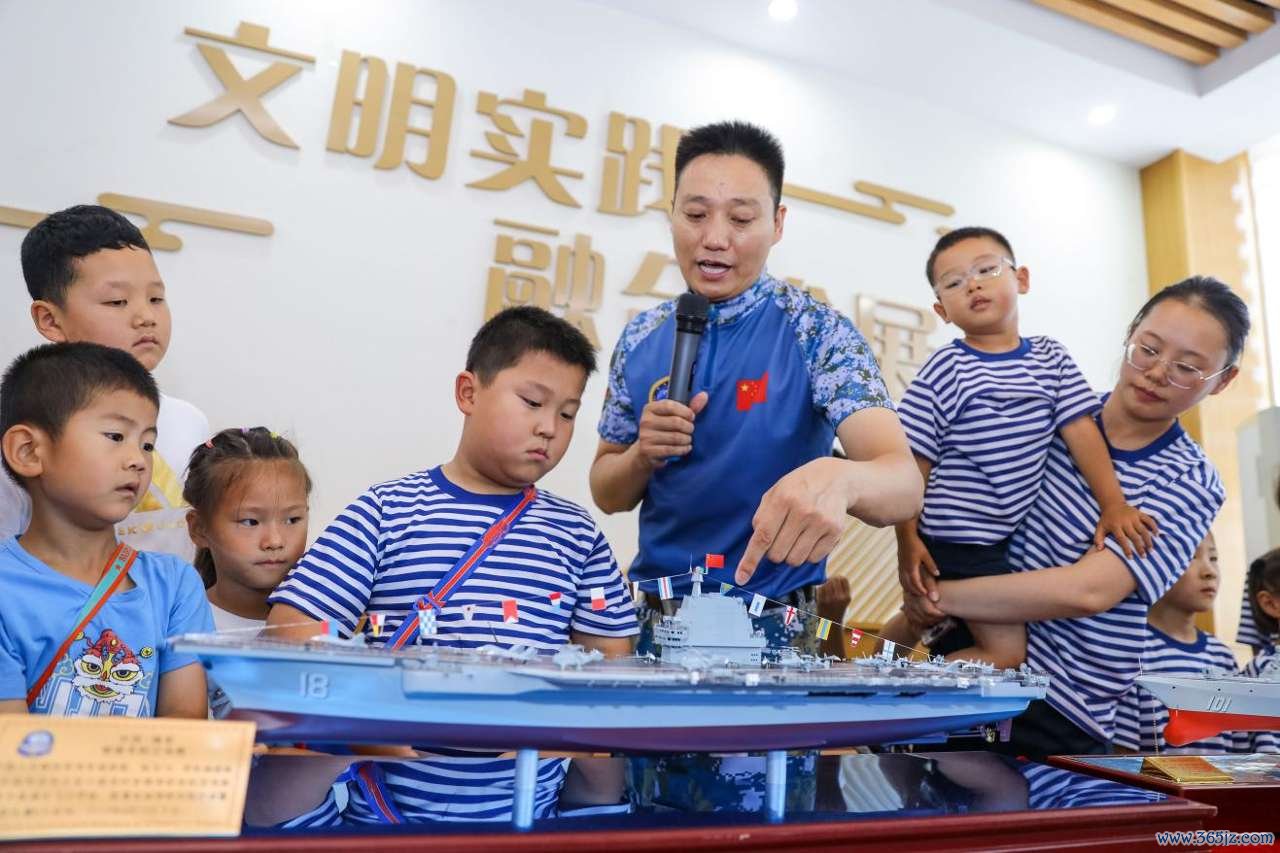 2026年7月30日，在山东省青岛西海岸新区滨海街道三沙路社区开展的“一海里的爱”公益活动中，爱基金逐梦深蓝讲师团讲师向小朋友介绍海军舰艇模型知识。张鹰 摄 (1)